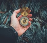 A close-up shot of a hand holding a vintage compass against a natural background.